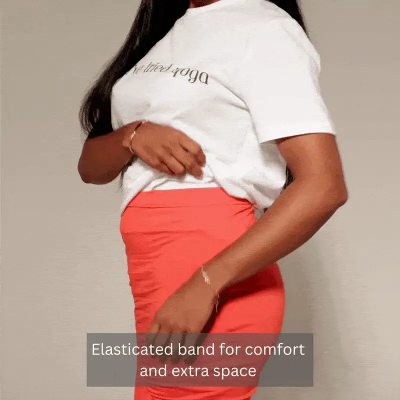 woman demonstrates the elastic waist band of a peach skirt